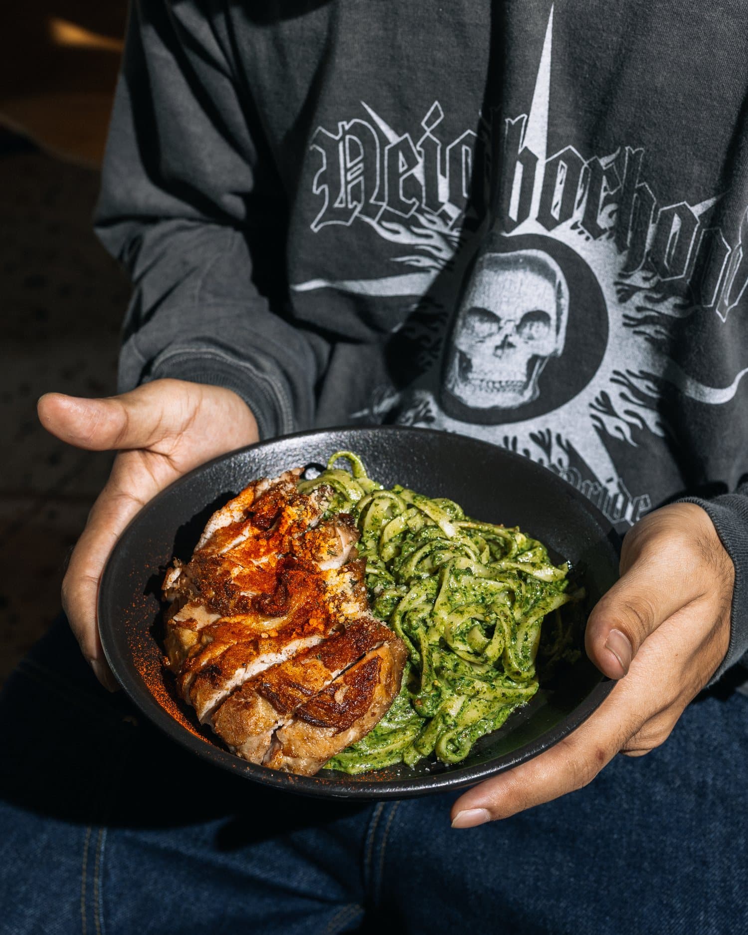 Crew member holding a plate of pesto pasta