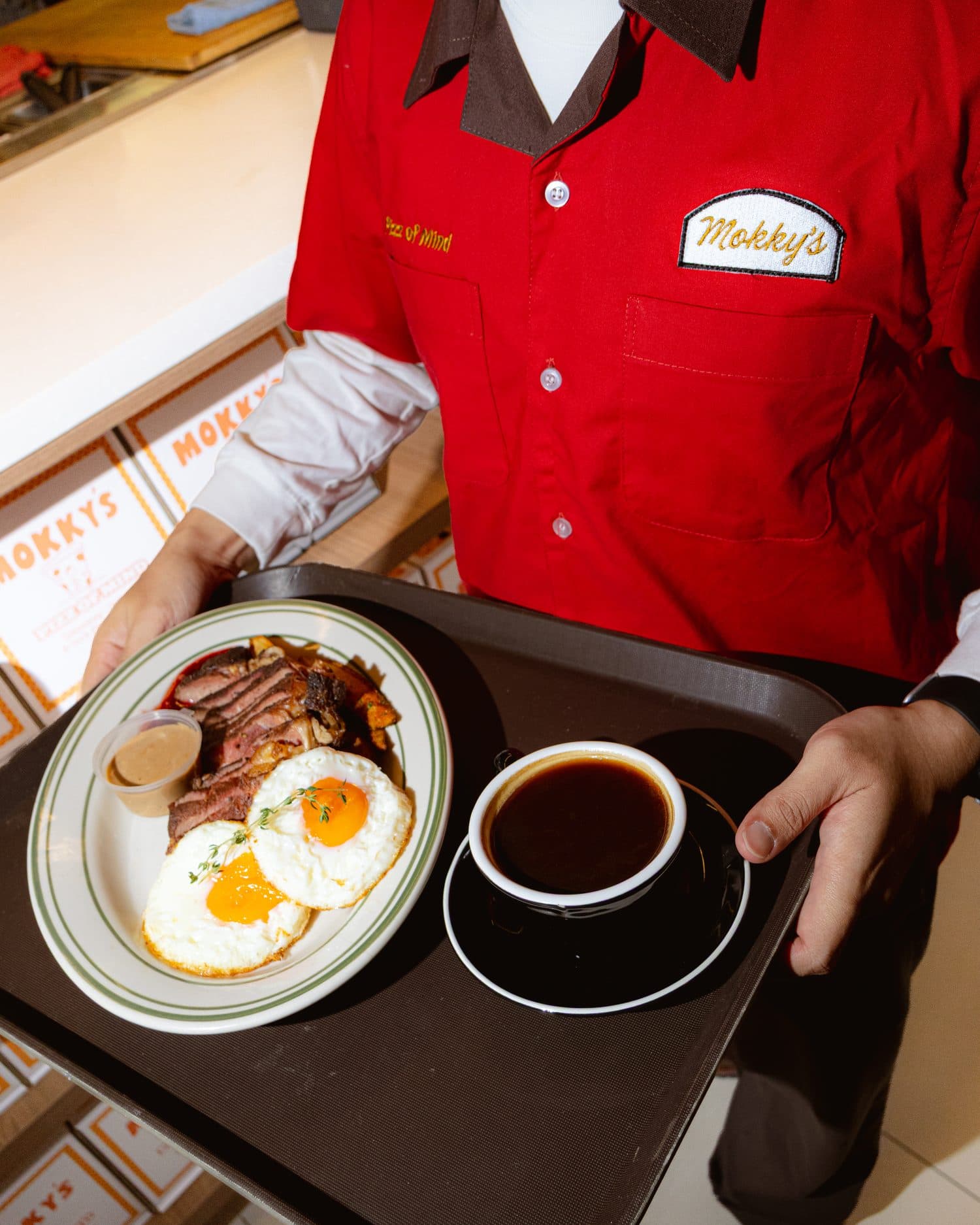 Crew member serving steak and eggs with a coffee