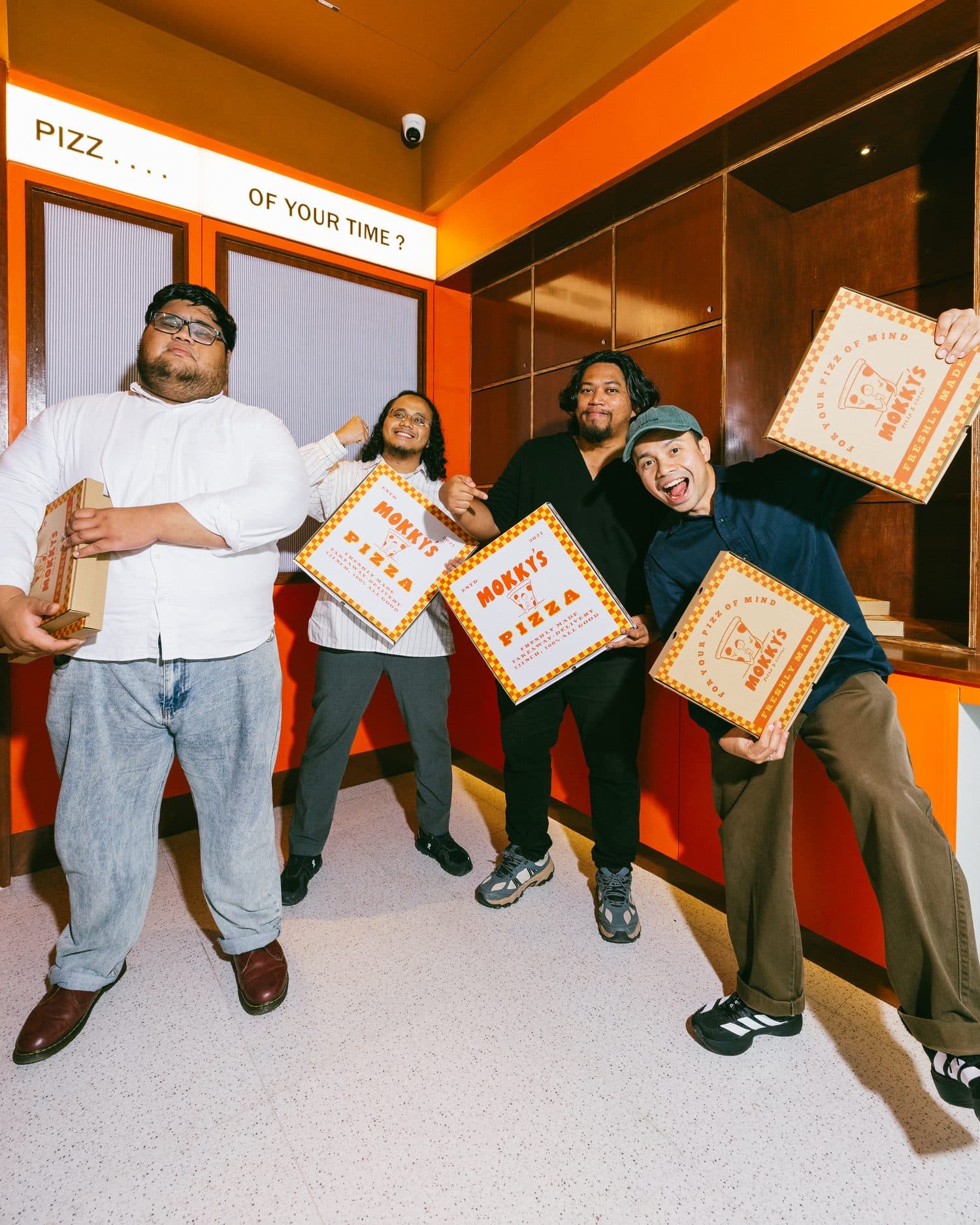 Four friends holding up Mokky's pizza boxes