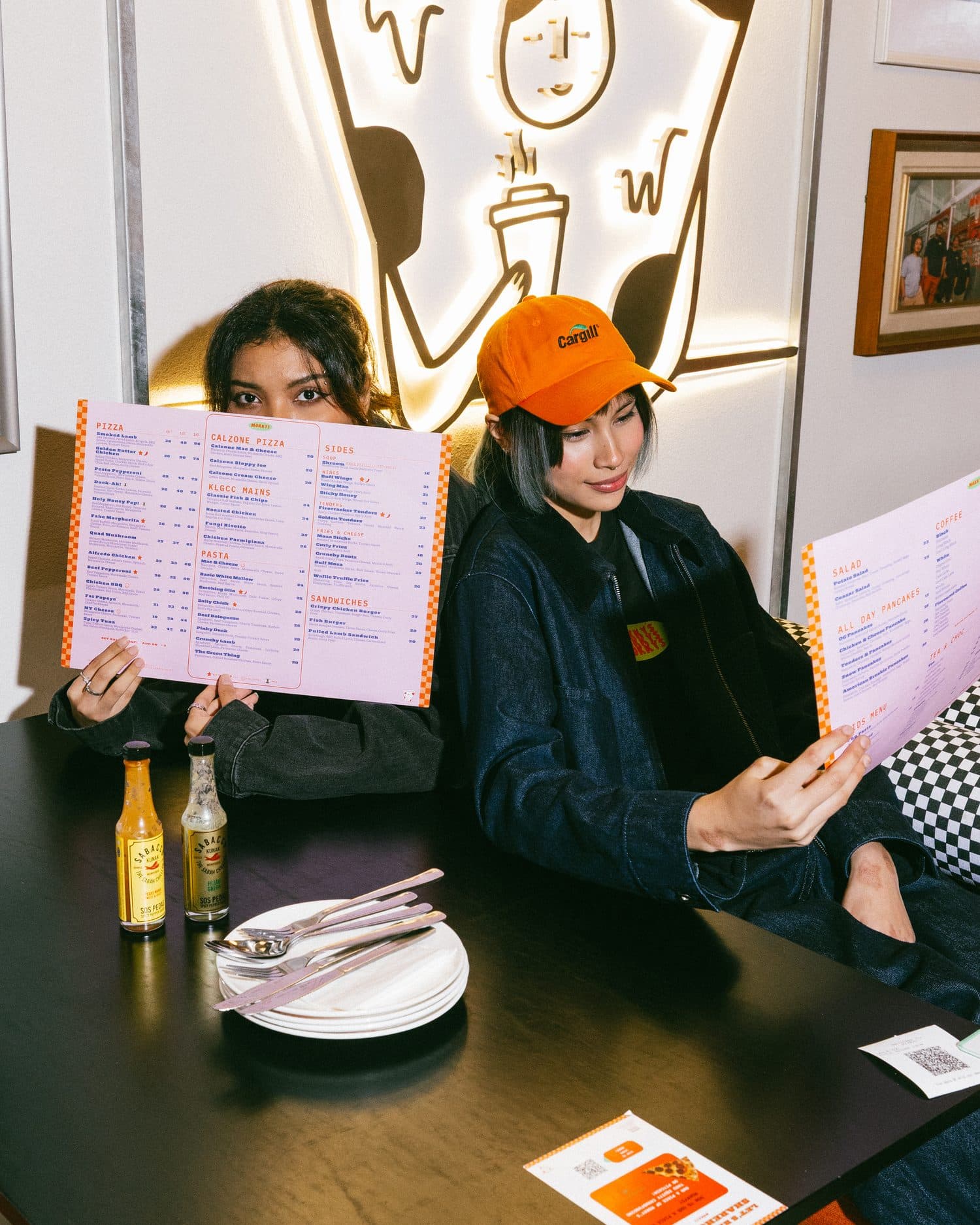Friends reading the Mokky's menu under the neon pizza sign