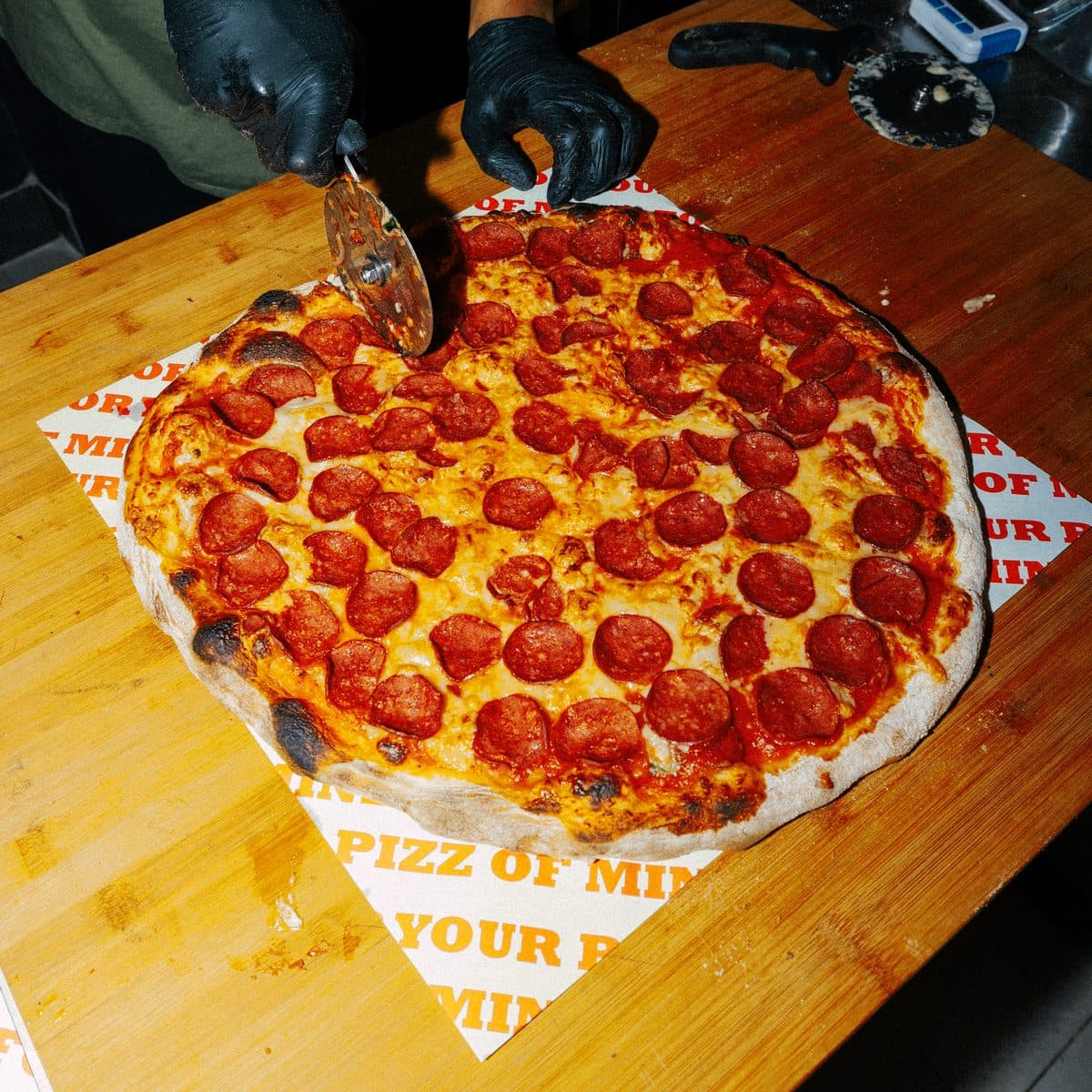Slicing a fresh pepperoni pizza
