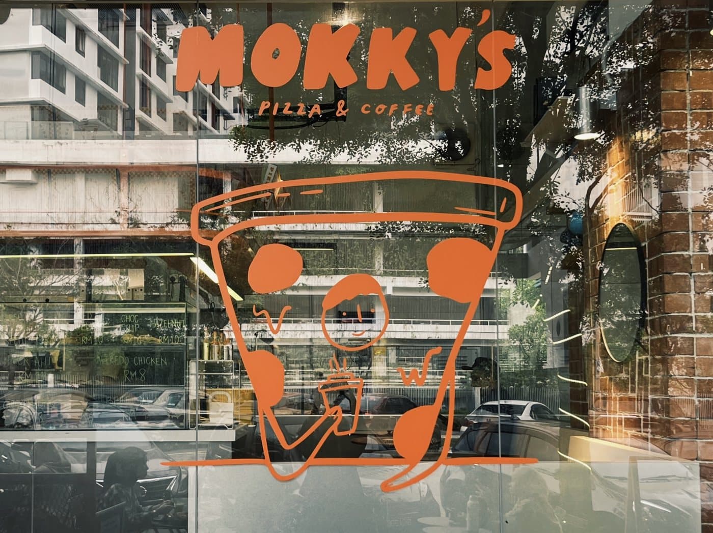The Mokky's Pizza & Coffee storefront with its Pizza Guy window decal